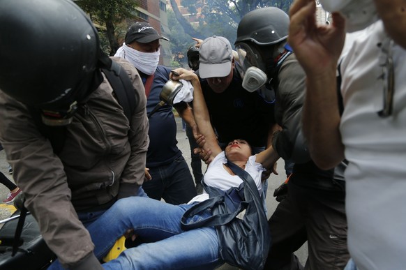 Protesters help a woman who was affected by tear gas during a march against hunger in Caracas, Venezuela, Saturday, June 3, 2017. In Venezuela, where eating is a daily odyssey for most families, hundr ...