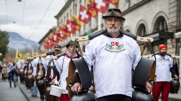 Des personnes manifestent contre la loi Covid-19 avec la presence des Freiheitstrychler lors d&#039;un rassemblement le samedi 13 novembre 2021 a Geneve. (KEYSTONE/Jean-Christophe Bott)