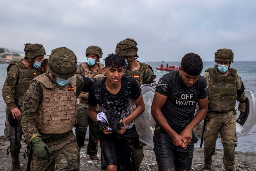 epa09213296 Spanish soldiers help migrants at their arrival at El Tarajal beach, in Ceuta, Spain, 19 May 2021. Spain&#039;s Government considers that the massive arrival of some 8,000 irregular migran ...