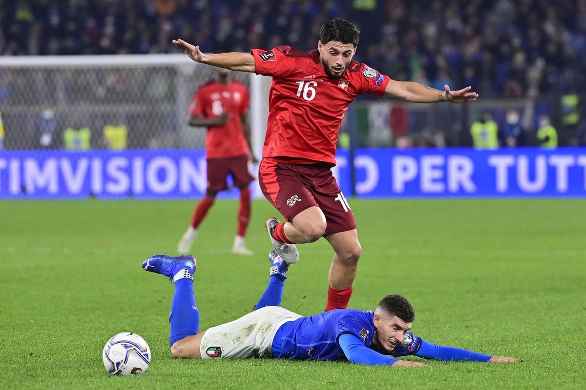 Switzerland's midfielder Kastriot Imeri, in red, fights for the ball against Italy's defender Giovanni Di Lorenzo, in blue, during the 2022 FIFA World Cup European Qualifying Group C match b ...