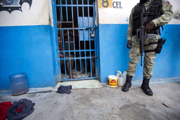 A police officer stands outside a room of inmates after a prison break at the Civil Prison in the coastal town of Arcahaiea, Haiti, Saturday, Oct. 22, 2016. Over 100 inmates escaped after they overpow ...