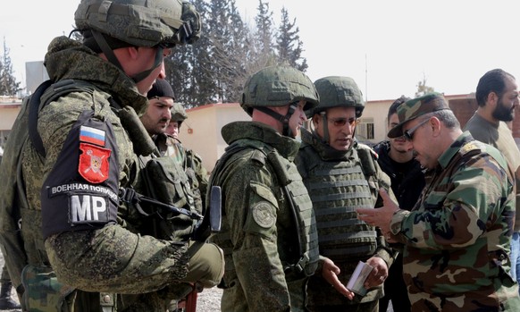 epa06570759 Syrian and Russian soldiers talk at the designated corridor at al-Wafidin Camp in the countryside of Damascus, Syria, 28 February 2018, as they are waiting for civilians willing to leave t ...