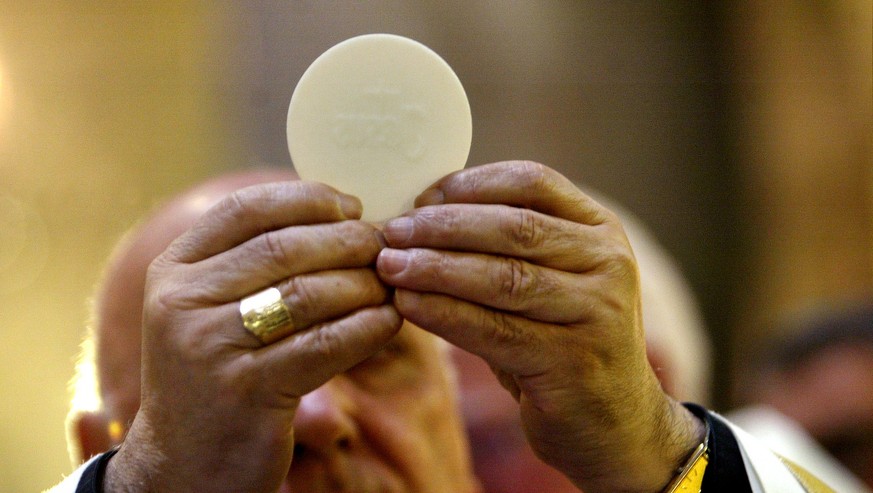 The Latin Patriarch of Jerusalem, Michel Sabbah, raises a communion wafer, which sybolizes the body of Christ, during the Pontifical Easter Mass, in Jerusalem, Easter Sunday, April 11, 2004. A few hun ...