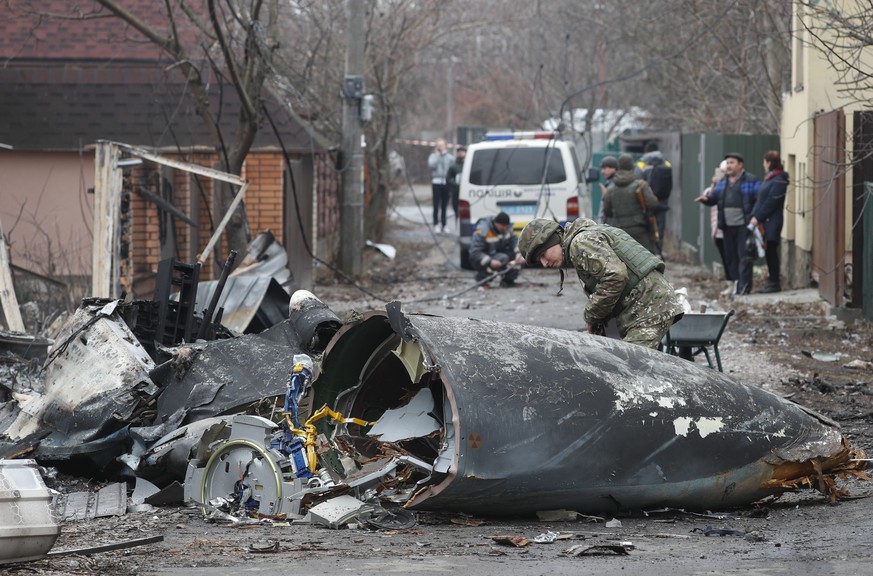 epa09783630 A soldier looks at the debris of a military plane that was shot down overnight in Kiev, Ukraine, 25 February 2022. Russian troops entered Ukraine on 24 February prompting the country&#039; ...