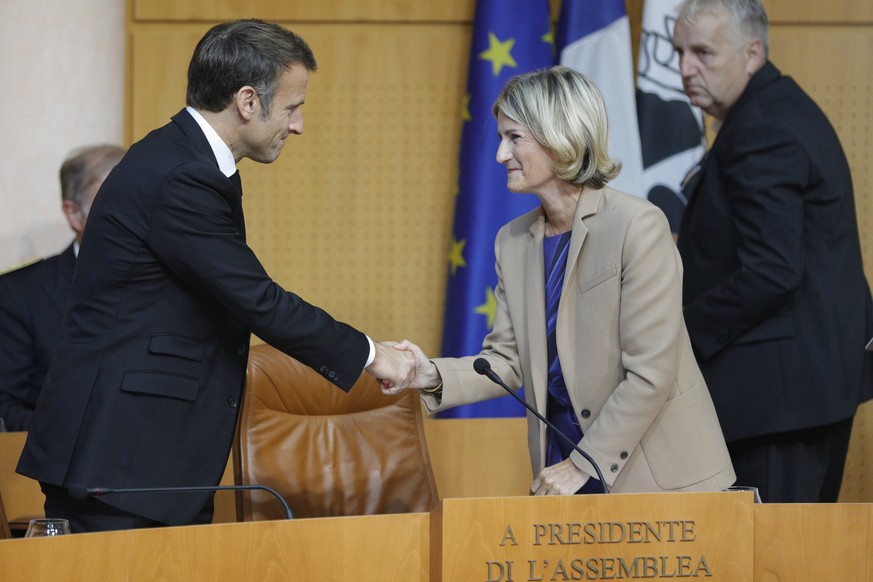 epa10887365 French President Emmanuel Macron (L) shakes hands with Marie-Antoinette Maupertuis (C), President of the Corsican Assembly, during a session at the Corsican Assembly, on the southern French island...