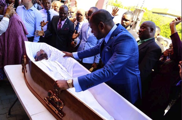 Pastor Alph Lukau lehnt sich über den vermeintlich toten Mann.