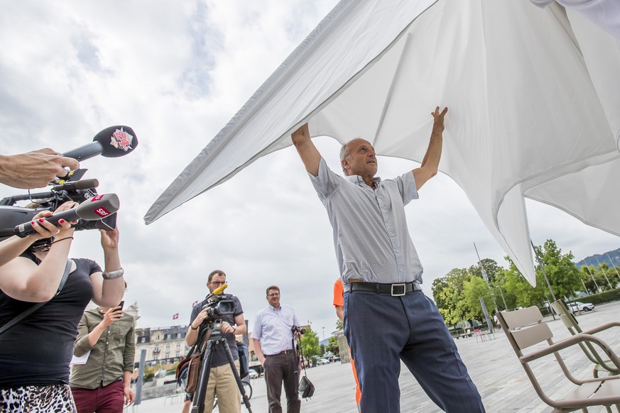 Zuercher Stadtrat Filippo Leutenegger oeffnet den ersten Sonnenschirm fuer eine zweimonatige Testphase auf dem Sechselaeutenplatz am Freitag 4. August 2017 in Zuerich. (KEYSTONE/Christian Merz)