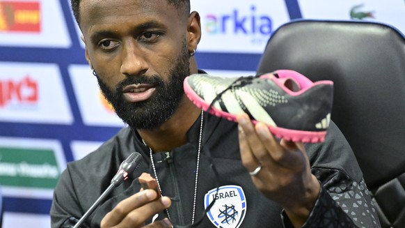 Israel team captain Eli Dasa shows a shoe of a kidnapped Israeli boy during a press conference, before a training session for the Euro 2024 group I qualifying soccer match between Israel and Switzerla ...