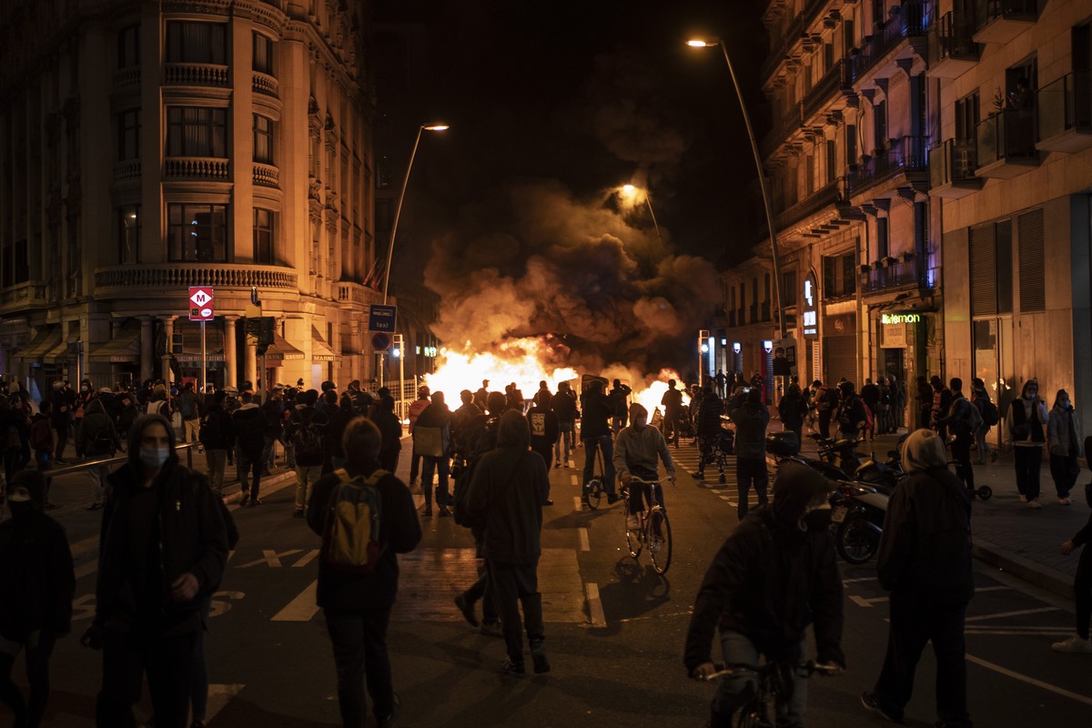 People gather next to a burning barricade during clashes after a protest condemning the arrest of rap singer Pablo Hasél in Barcelona, Spain, Wednesday, Feb. 17, 2021. Police fired rubber bullets and  ...
