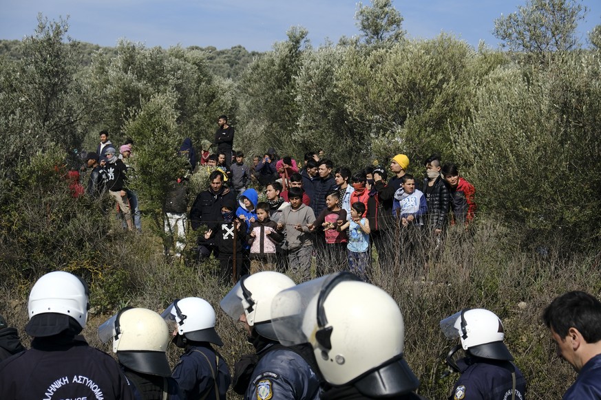 Police block a road as migrants look on during clashes outside the Moria refugee camp on the northeastern Aegean island of Lesbos, Greece, on Monday, March 2, 2020. Thousands of migrants and refugees  ...