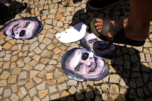 Demonstrators stomp on masks representing Brazilian President Jair Bolsonaro as they protest his government&#039;s handling of the COVID-19 pandemic outside Planalto presidential palace in Brasilia, B ...