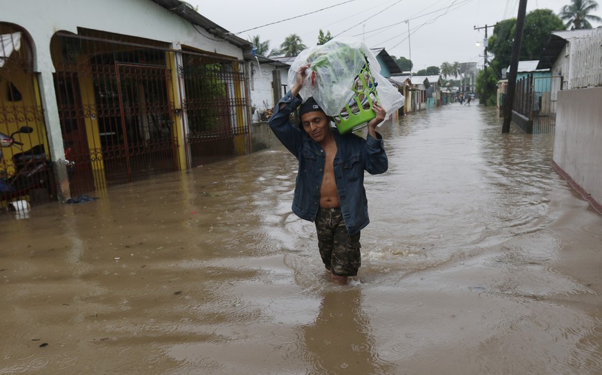 A man walks in knee-deep floodwaters carrying belongings in San Manuel, Honduras, Wednesday, Nov. 4, 2020. Eta weakened from the Category 4 hurricane to a tropical storm after lashing the Caribbean co ...