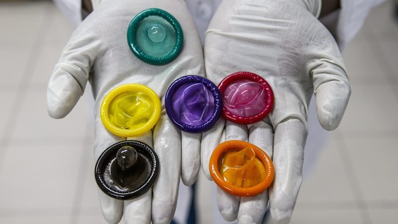 epa04613963 A picture made available on 11 February 2015 shows a worker holding a variety of colored condoms at the Karex condom factory in Port Klang, Malaysia, 17 January 2015. Karex is one of the w ...