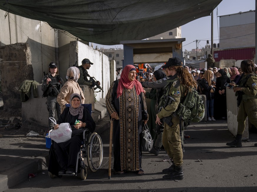 Israeli security forces check the identities of Palestinian women at the Qalandia checkpoint as they make their way to pray at the Al-Aqsa Mosque in Jerusalem on the fourth Friday of the Muslim holy m ...