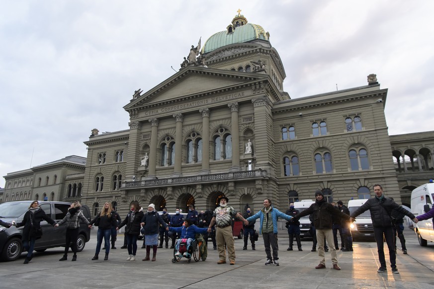 Leute bilden eine Menschenkette und demonstrieren vor dem Bundeshaus gegen die Corona-Schutzmassnahmen des Bundes, am Samstag, 19. Dezember 2020, auf dem Bundesplatz in Bern. (KEYSTONE/Anthony Anex)