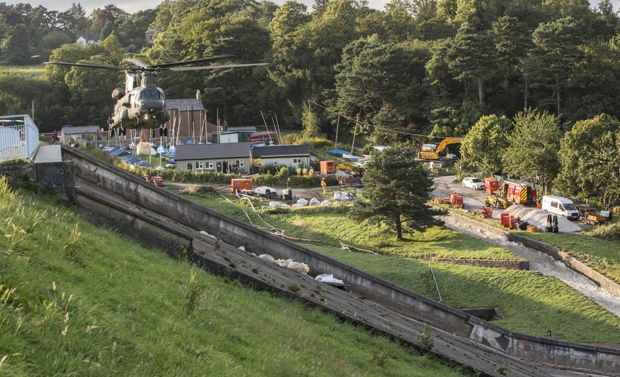 epa07754109 A handout picture provided by the British Ministry of Defence showing a British Royal Air Force Chinook Mk6a helicopter approaching with the load to drop on the dam in Whaley Bridge, Derby ...