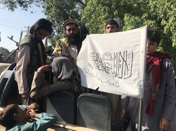 epa09415067 Taliban militants display their flag after taking control of Jalalabad, in Nangarhar province, Afghanistan, 15 August 2021. The Taliban have reached the outskirts of Kabul, the capital cit ...