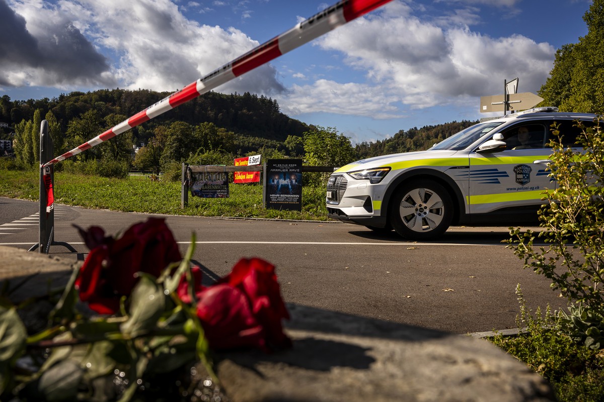 KEYPIX - A police car drives past flowers that have been laid down in a near the Schachen horse racing track, the site of a rave party, following a deadly shooting incident on Sunday, in Aarau Switzer ...