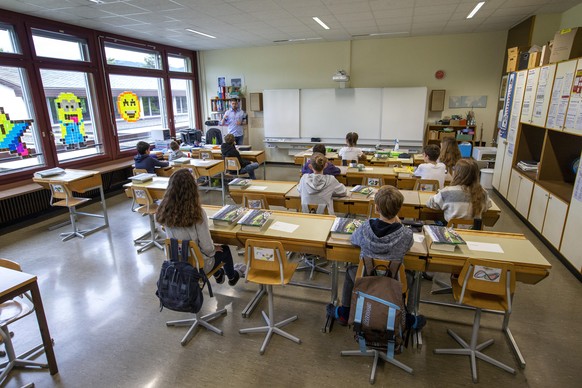 epa08414289 Teacher Sylvain talks to half of his pupils in a classroom at a primary school, in Lully near Geneva, Switzerland, 11 May 2020. In Switzerland from today, the Swiss authorities lifted seco ...