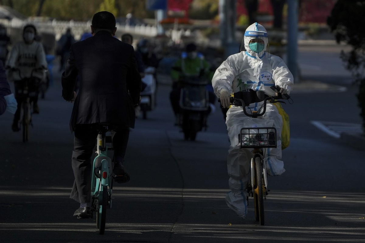A worker in protective gear rides on a street as she heads to take COVID-19 sample from residents who have been under home quarantine in Beijing, Thursday, Nov. 3, 2022. The ruling Communist Party is  ...