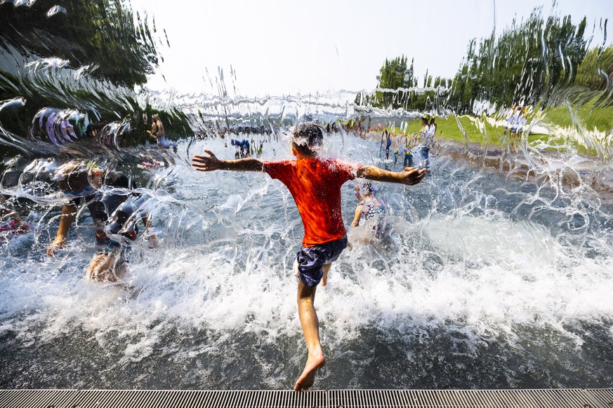 epa09329885 Children cool off in a waterfall at The Yards Park during hot, humid weather in Washington, DC, USA, 07 July 2021. After historic heat waves gripped some parts of the country, the nation&# ...