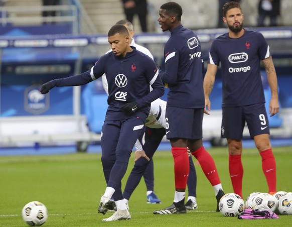 France's Kylian Mbappe, left, kicks a ball next to Paul Pogba and Olivier Giroud, right, during warmup before the UEFA Nations League soccer match between France and Portugal at the Stade de France in Saint-Denis, north of Paris, France, Sunday, Oct. 11, 2020. (AP Photo/Thibault Camus)
