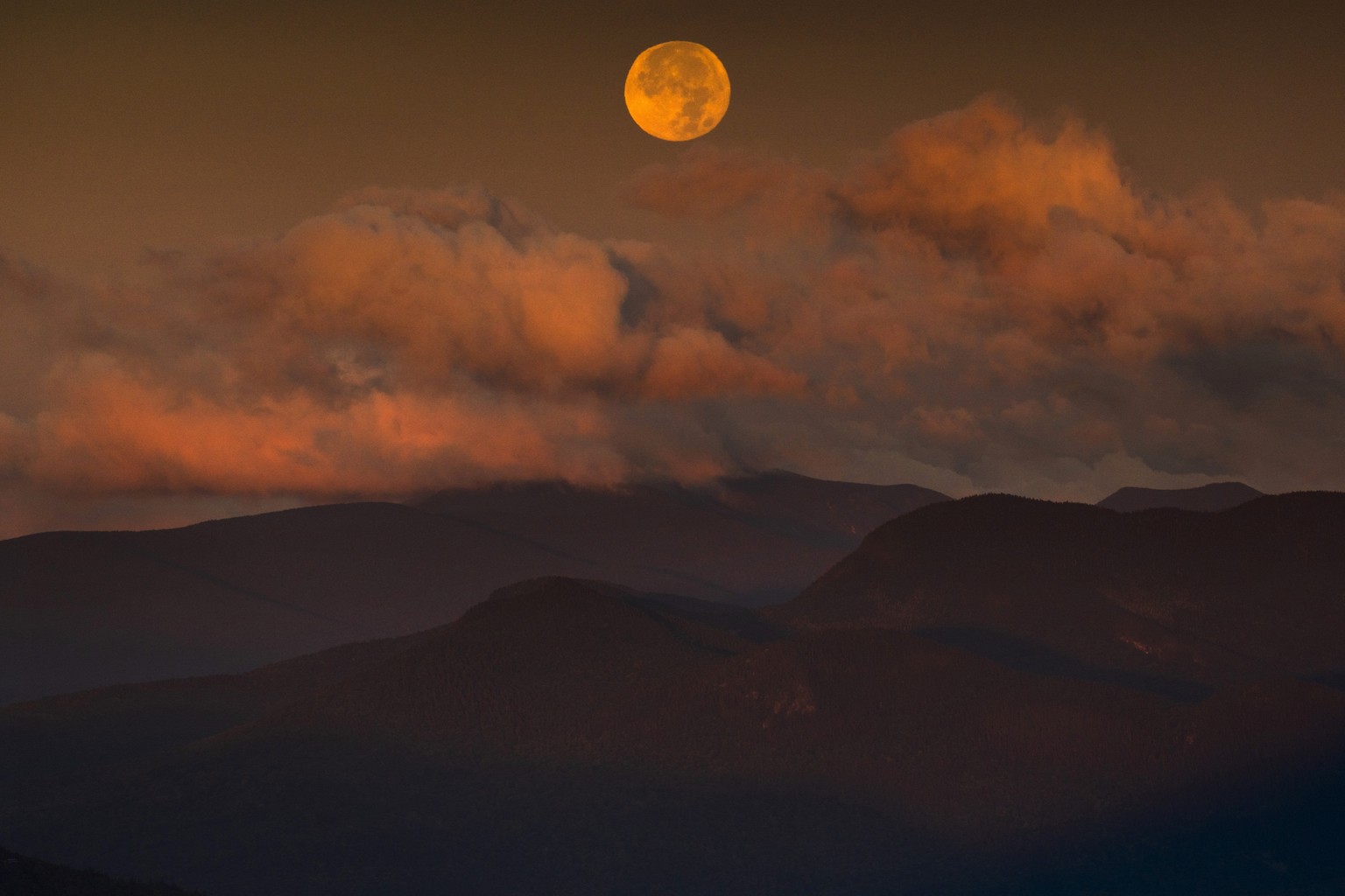 The blue supermoon sets over the White Mountain National Forest at sunrise, Thursday, Aug. 31, 2023, in Carroll County, New Hampshire. The next blue superman won't occur until 2037. (AP Photo/Rob ...