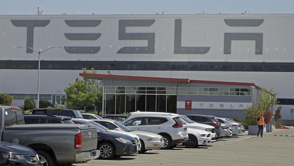 A masked man walks in the Tesla plant parking lot Monday, May 11, 2020, in Fremont, Calif. The parking lot was nearly full at Tesla&#039;s California electric car factory Monday, an indication that th ...