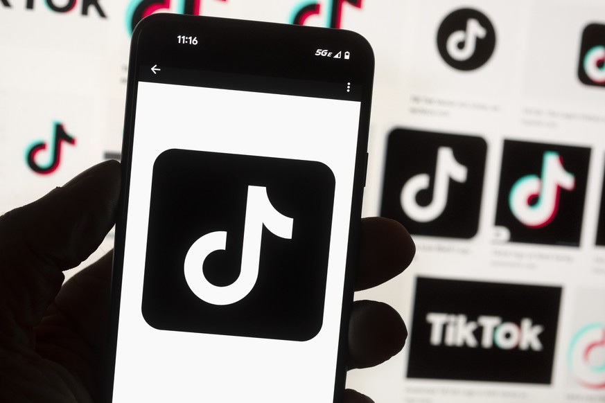 FILE - The TikTok logo is displayed on a mobile phone in front of a computer screen, Oct. 14, 2022, in Boston. A measure set to force TikTok&#039;s parent company to sell the video-sharing platform or ...