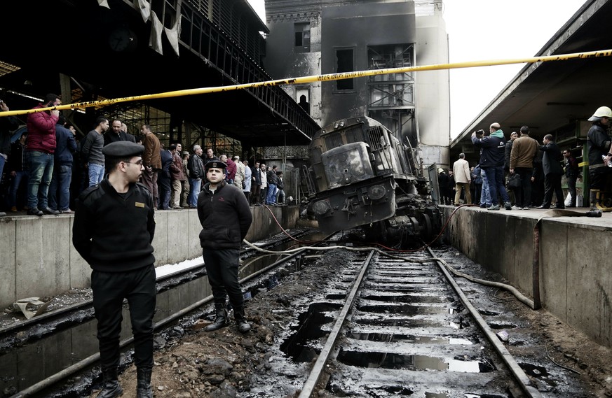 Policemen stand guard in front of a damaged train inside Ramsis train station in Cairo, Egypt, Wednesday, Feb. 27, 2019. An Egyptian medical official said at least 20 people have been killed and dozen ...