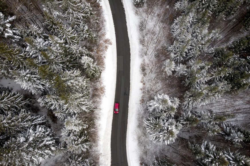 Ein Auto fährt auf der Strasse des «Col du Mollendruz» neben Schnee und gefrorenen Bäumen im Jura im Februar 2019.