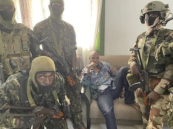 epa09449661 A handout photo made available by Guinea military shows Alpha Conde, President of the Republic of Guinea (C) detained by army special forces in Conakry, Guinea 05 September 2021. According ...