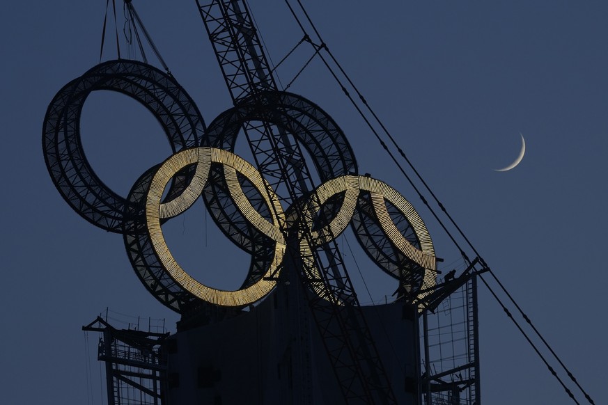 A worker labors to assemble the Olympic Rings onto of a tower on the outskirts of Beijing, China, Wednesday, Jan. 5, 2022. Beijing will host the Winter Olympics in a month&#039;s time, making it the w ...