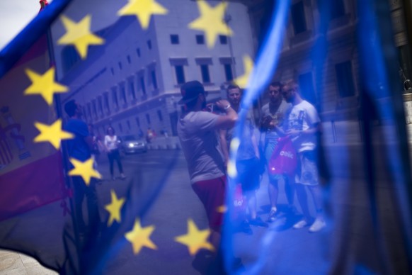 In this Friday, June 24, 2016 photo, tourists posing for a photograph in front of the Spanish Parliament is seen through the EU flag in Madrid, Spain. The news of the U.K. vote to quit the European Un ...