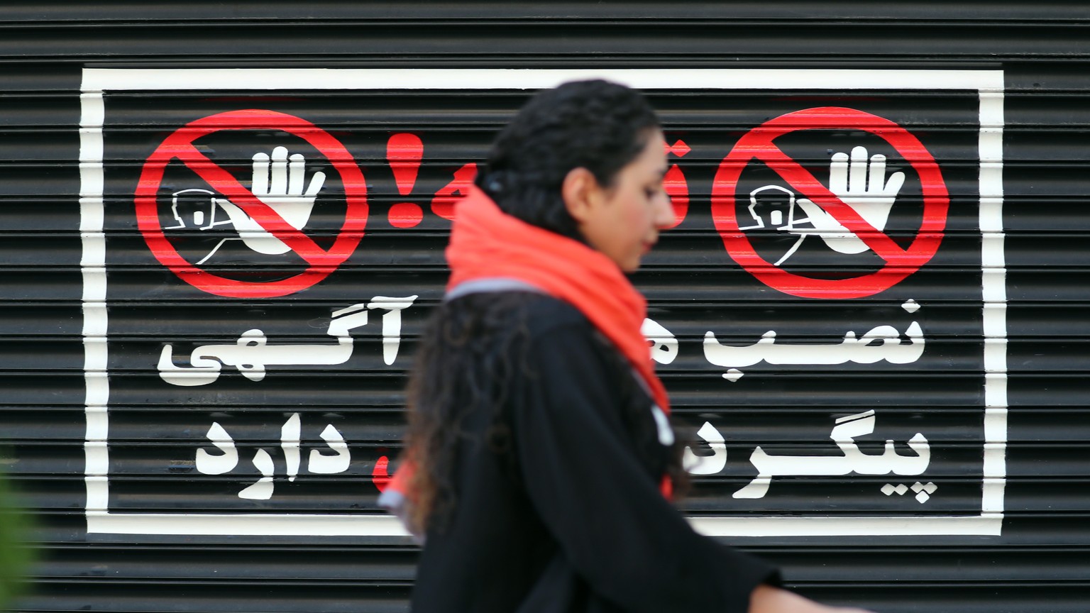epaselect epa10793376 An Iranian woman walks next to a closed shop without wearing a headscarf, in Tehran, Iran, 10 August 2023. Iran