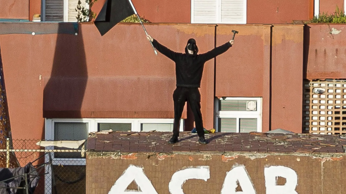 Ein Hausbesetzer steht mit einer schwarzen Flagge und einem Hammer auf dem Dach des Gebäudes: Die Polizei hat die Besetzer der Gebäude "La Ruina" und "El Kubo" im Stadtteil Sant Ge ...
