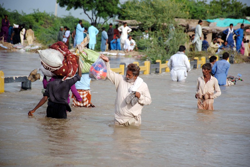 epa10146982 People wade through a flooded area following heavy rains in Jhuddo District, Sindh province, Pakistan, 30 August 2022. According to the National Disaster Management Authority (NDMA) on 27  ...