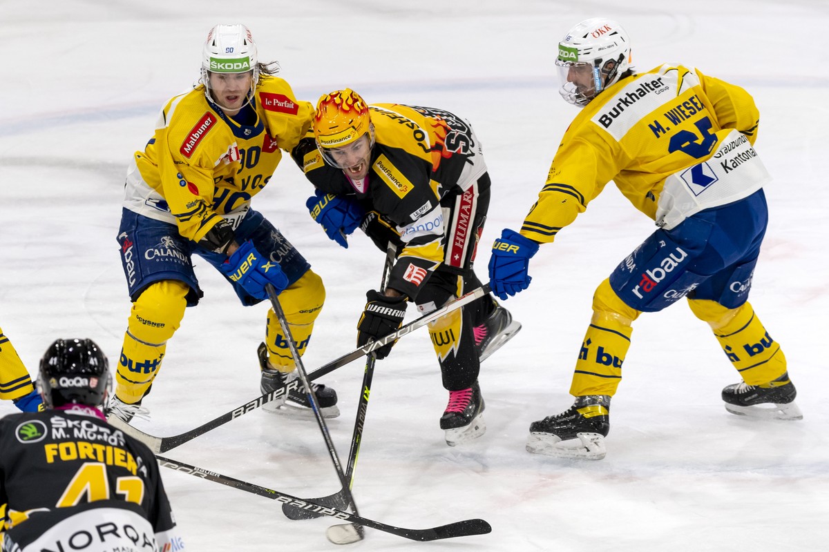 Davos' Sven Jung, links, und Marc Wieser, rechts, gegen Ajoies PostFinance Top Scorer Philip-Michael Devos, Mitte, beim Eishockey-Qualifikationsspiel der National League zwischen dem HC Ajoie und ...