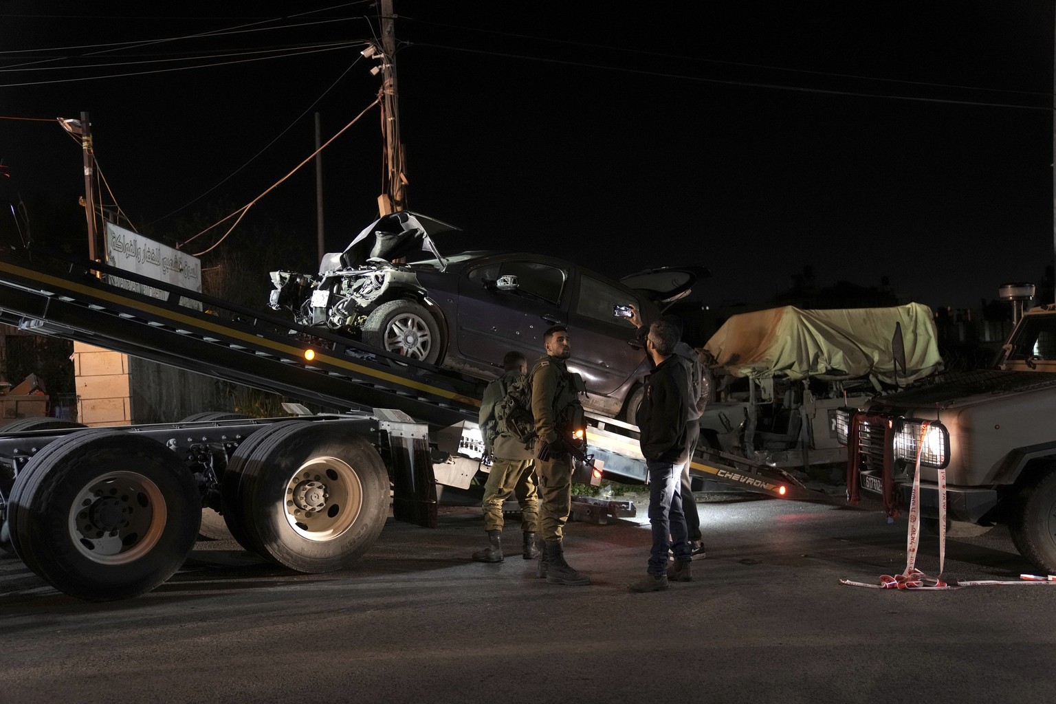 Israeli forces remove a civilian car used in a suspected ramming attack in Beit Ummar, Saturday, April 1, 2023. The Israeli military said a Palestinian driver rammed his vehicle into a group of Israel ...