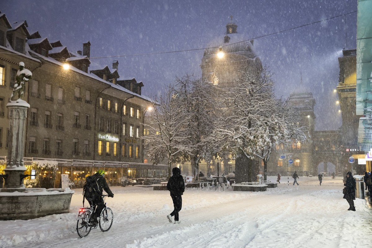 Passanten gehen und fahren mit dem Fahrrad auf dem Baerenplatz vor dem Bundeshaus durch den Schnee, am Donnerstag, 21. November 2024 in Bern. (KEYSTONE/Peter Klaunzer)