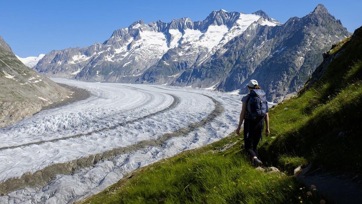 A woman walks next to the Swiss Aletsch Glacier during a beautiful summer day above Bettmeralp in Wallis, Switzerland, this Sunday, July 8, 2018. The Swiss Aletsch glacier, one of the largest ice stre ...