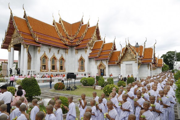 epa12204382 Newly ordained hill tribe Buddhist monks holding lotus flowers and joss sticks walk in a circular procession during the 60th annual mass ordination ceremony for hill tribe men and youngste ...