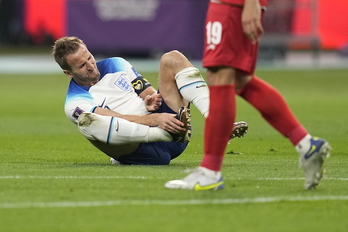 England's Harry Kane grabs his foot after a collision with Iran's Morteza Pouraliganji during the World Cup group B soccer match between England and Iran at the Khalifa International Stadium ...