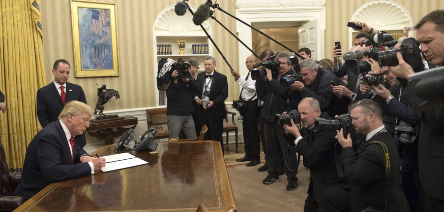 epa05736676 US President Donald J. Trump (L) signs his first executive order as president, ordering federal agencies to ease the burden of former President Barack Obama&#039;s Affordable Care Act, aft ...