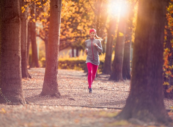 Frau joggt durch den herbstlichen Wald