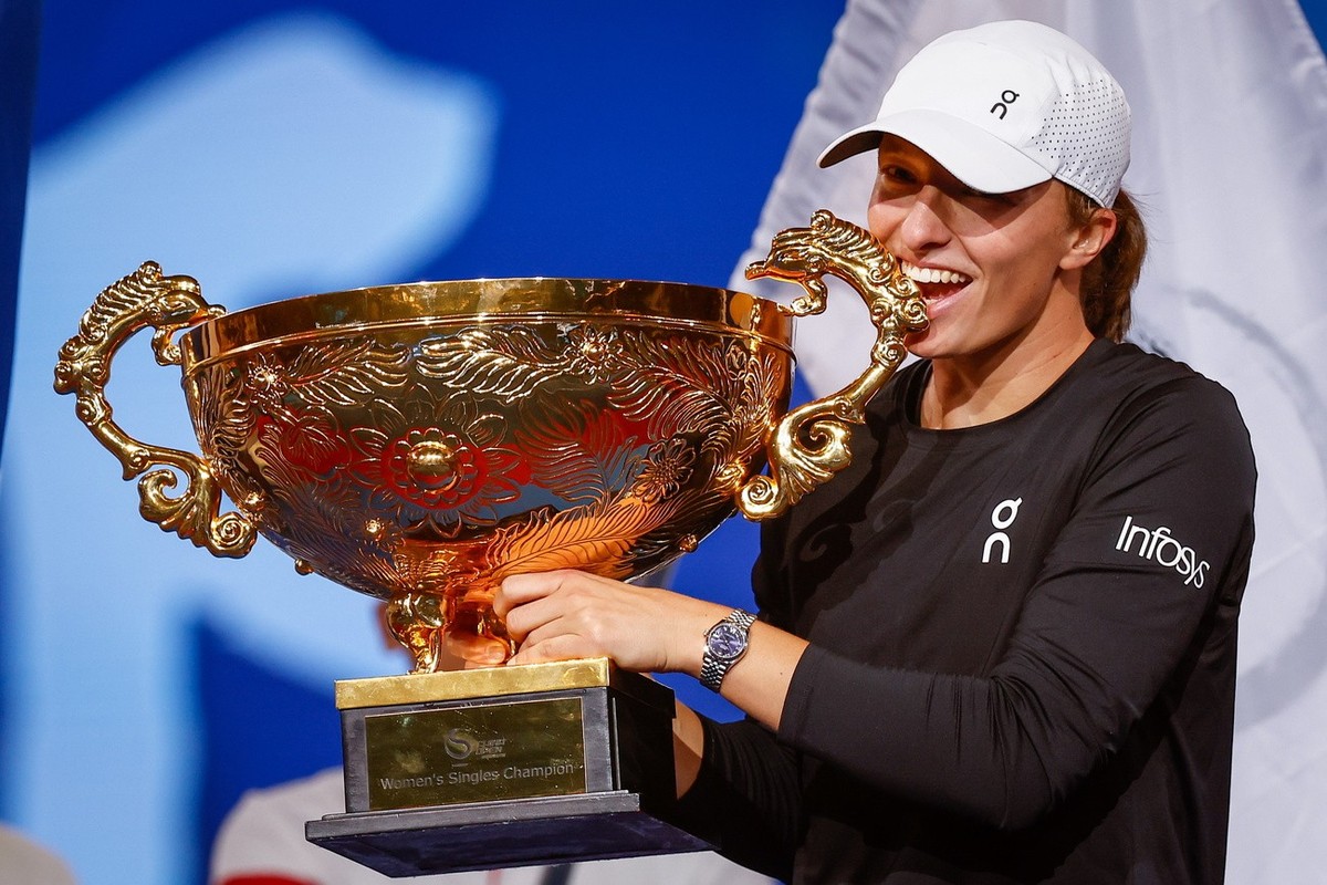 epa10907300 Iga Swiatek of Poland bites her trophy after winning the Women's Singles Final match against Liudmila Samsonova of Russia (not pictured) at the China Open tennis tournament in Beijing ...
