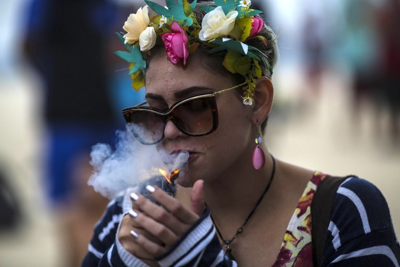 epa05293994 A woman smokes marijuana during a demonstration calling for the legalization of marijuana at Ipanema beach in Rio de Janeiro, Brazil, 07 May 2016. The annual Global Marijuana March is taki ...