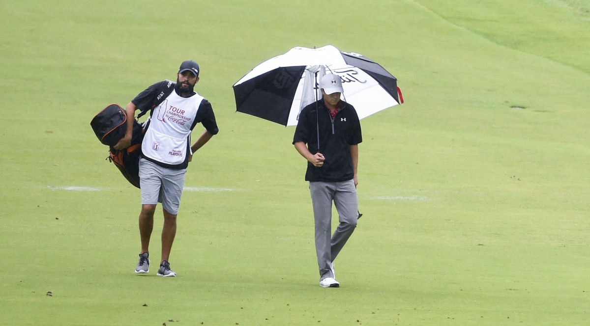 Das Bild, das die Welt von Caddies hat: Greller muss im Regen Spieths Tasche schleppen, während der lässig mit der Hand im Hosensack unterm Schirm zum Loch schlendert.