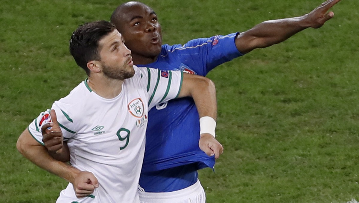 Italy's Angelo Ogbonna jumps for the ball next to Northern Ireland's Will Grigg during the Euro 2016 Group E soccer match between Italy and Ireland at the Pierre Mauroy stadium in Villeneuve ...