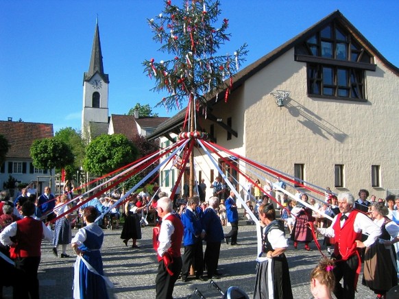 Der Maibaum auf dem Dorfplatz in Reinach BL wird besungen und umtanzt.
